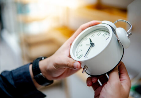 Male hand adjusting the time on white clock